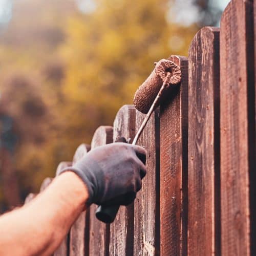 Painting a fence with a roller